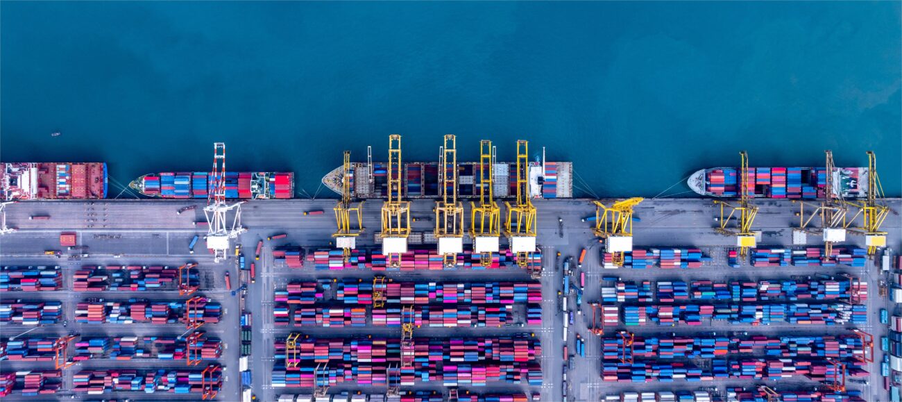 Top down aerial view of a sea port terminal with rows of stacked shipping containers